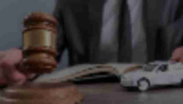 Man holding a gavel with a toy car next to it and an open book in front of him, ready to answer what happens to your car after an accident.